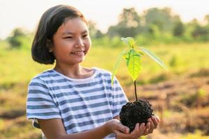 barn som håller litet träd för plantering i naturen. koncept rädda jorden foto