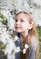 söt liten flicka i en blommande vårträdgård foto