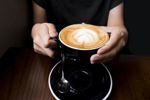 kaffe latte i handen. mörk bakgrund foto