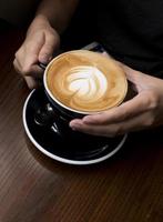kaffe latte i handen. mörk bakgrund foto