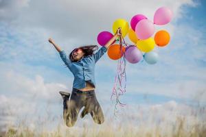 vacker flicka hoppar med ballonger på stranden foto