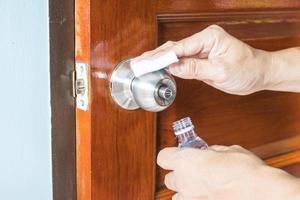 förebyggande rengöring av dörrhandtag med desinficerande lösning för att döda coronavirus på ytor vid beröring, koncept coronavirus covid19 foto
