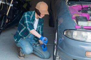 kvinnlig mekaniker fixar bil i ett garage foto