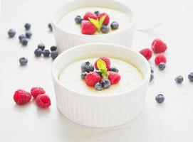 cheesecake dekorerad med hallon, blåbär och mynta i två ramekin, läcker dessert foto