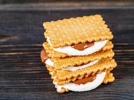 smores, marshmallowsmörgåsar - traditionella amerikanska söta chokladkakor på mörkt träbord, sidovy foto