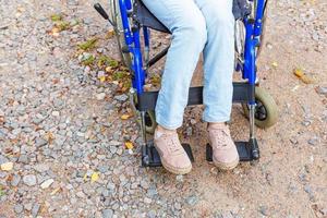 ben fötter handikapp kvinna i rullstol hjul på väg i sjukhus park väntar på patienttjänster. oigenkännlig förlamad tjej i invalid stol för funktionshindrade utomhus. rehabiliteringskoncept. foto