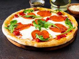 varm hemlagad italiensk pizza margherita med mozzarella och tomater på mörkbrunt stenbord, sidovy foto
