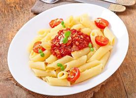 pennepasta med bolognesesås, parmesanost och basilika foto