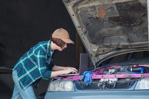 kvinnlig mekaniker fixar bil i ett garage foto