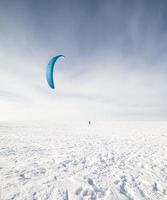 kiteboarder med blå drake på snön foto