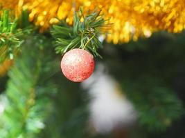 dekorerade julgröna träddekorationer har presentask guldröd boll hängande tall, löv på suddig bakgrund foto