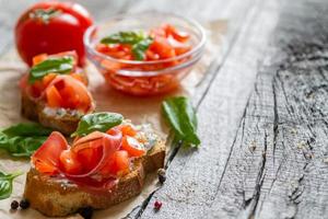 tomatbruschetta och ingredienser - bröd, tomat, hamon foto