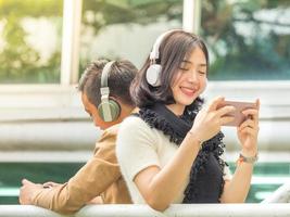 ung pojke och flicka spelar spel och lyssnar på musik på sina mobiltelefoner foto