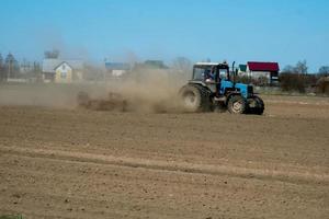 bonde i traktor som förbereder mark med såbäddskultivator som en del av försåddsaktiviteter under tidig vårsäsong av jordbruksarbeten på jordbruksmarker. foto
