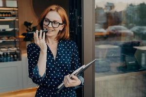 kvinnlig frilansare står utomhus med mobiltelefon och använder röstigenkänningssystem på smartphone foto