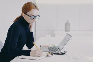 europeisk kvinna koncentrerad rekryterare gör pappersarbete och finansiell analys på kontoret. foto