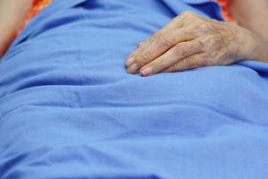 en äldre eller äldre kvinna ligger och hans hand på det blå tyget. hälsovård och medicinsk koncept. foto