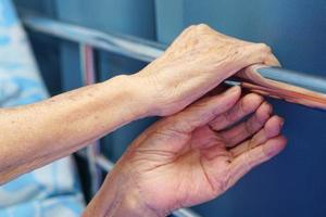 händerna på en äldre eller äldre gammal kvinna patient som greppa vid kanten av sängen. hälsovård och medicinsk koncept. foto