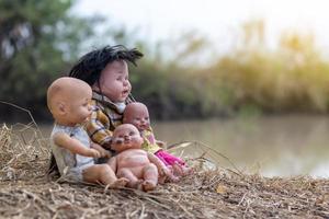 baby docka familj sitter på torrt gräs. foto