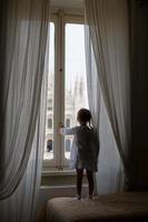 bedårande liten flicka som tittar ut genom fönstret på duomo, milan, italy