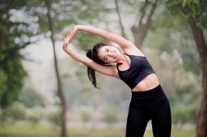 en vacker asiatisk kvinna värmer upp, för att göra musklerna flexibla innan du går till jogging foto