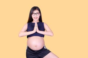 vackra asiatiska gravida kvinnor står på golvet och kopplar av med yogaträning foto