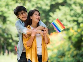 asiatiska par visar hbt-symbolen och omfamnar varandra med kärlek och lycka foto