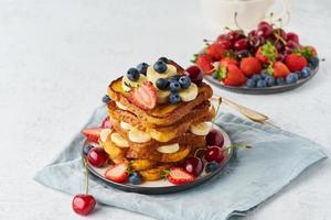 french toasts med bär och banan, brioche frukost, vit bakgrund, närbild foto