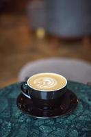 en kopp cappuccino med skum på ett marmorbord i ett mysigt litet kafé. dryck foto