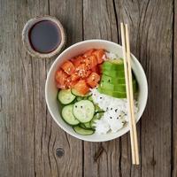 laxskål med färsk fisk, ris, gurka, avokado foto