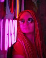 flicka i neonljus, vacker kvinna i solglasögon, med rosa hår, med dreadlocks pigtails foto