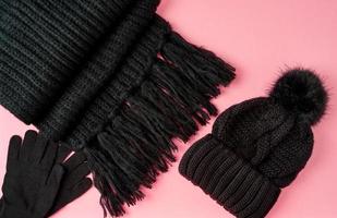 platt liggande vinter- eller höstvarma kvinnatillbehör - svart stickad halsduk, mössa, foto