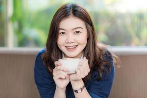 glad asiatisk le kvinnlig student som dricker kaffe foto