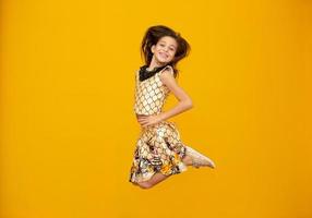porträtt av ett lyckligt leende barn flicka i gul bakgrund. foto