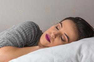 vacker kvinna sover på bekväm kudde i sängen hemma foto
