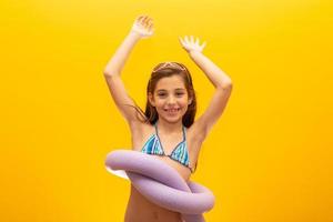 barn som bär bikini på gul bakgrund. begreppet sommar, strand och pool. foto