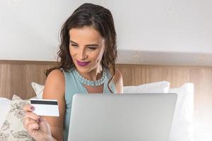 ung kvinna med kreditkort och använder bärbar dator. online shopping koncept foto
