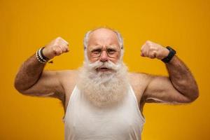 gammal man med långt vitt skägg som visar sin styrka med armarna foto