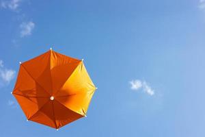 en närbild från det låga, ett vackert, genomskinligt orange paraply som svävar fritt. foto