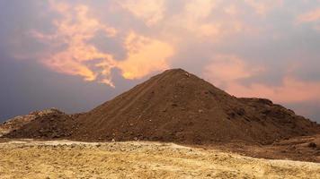 utsikt över en stor mängd brun lerjord staplad som berg på gul sand. foto