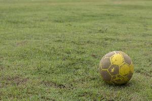 gammal gul fotboll på gräsmattan. foto