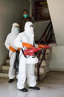 båda männen, iklädda ppe-uniformer, sprayade för att rengöra trappan. foto