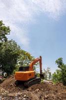 orange backhoe skinkor på högen nära träden. foto