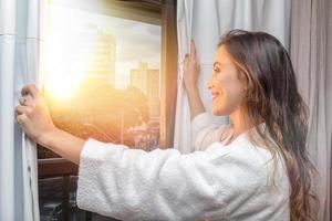 människor och hopp koncept - närbild av glad kvinna som öppnar fönstergardiner foto