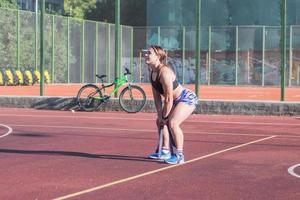 ung stark kvinna tränar utomhus på sommaren, kvinnlig professionell idrottare gör övningar i parken foto
