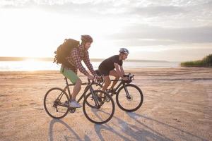 två unga män på en turcykel med ryggsäckar och hjälmar i öknen på en cykeltur foto