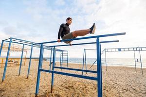 unga vältränade manliga träning gör övningar utomhus på stranden foto