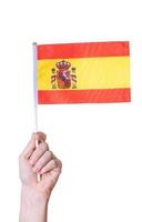 en hand håller Spaniens flagga på en vit isolerad bakgrund. foto