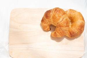 croissant isolerad på träplatta, nybakat bröd för enkel frukost. foto