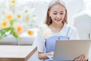 ung asiatisk tjej använder laptop hemma foto